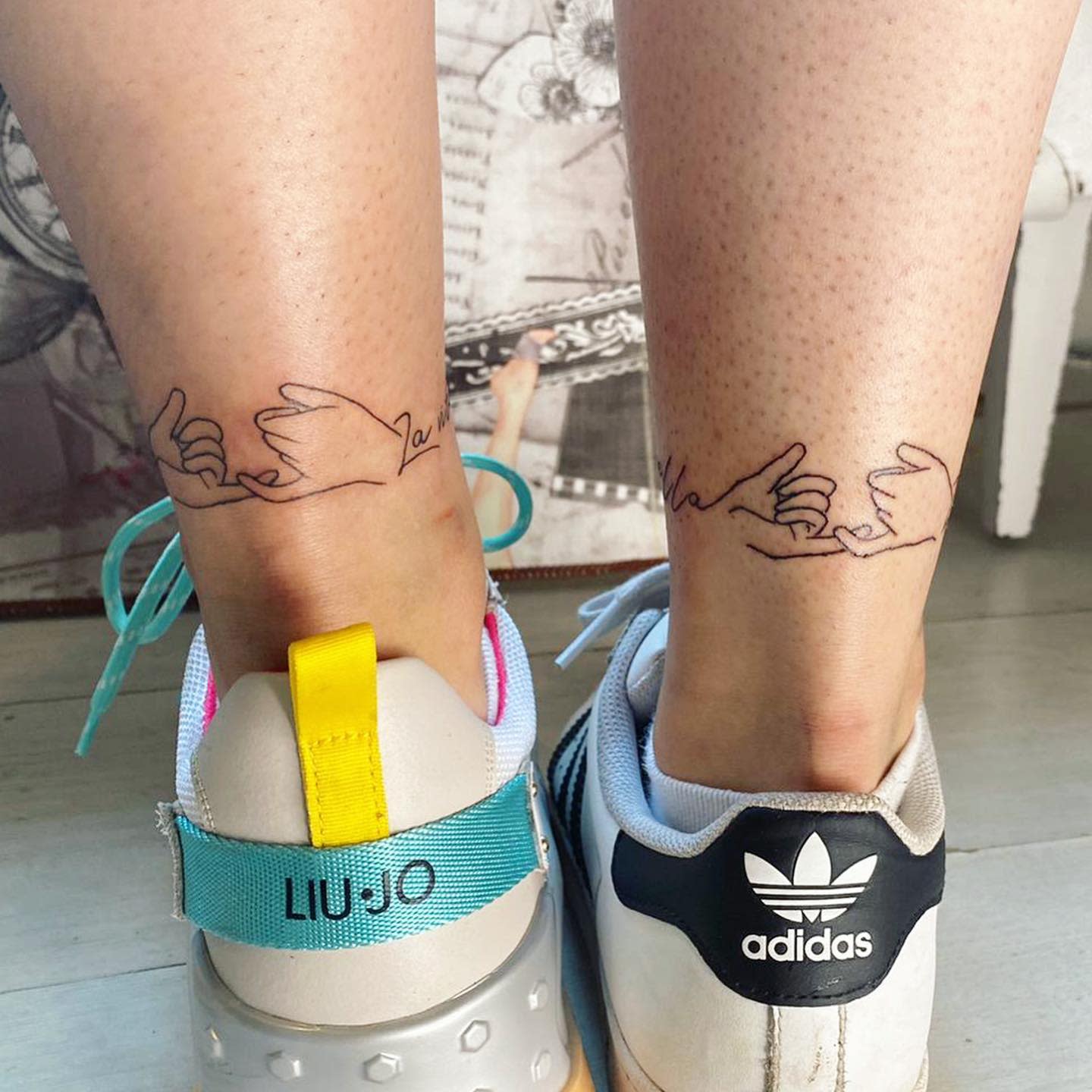 Minimalist tattoos of linked pinky fingers on back of ankles